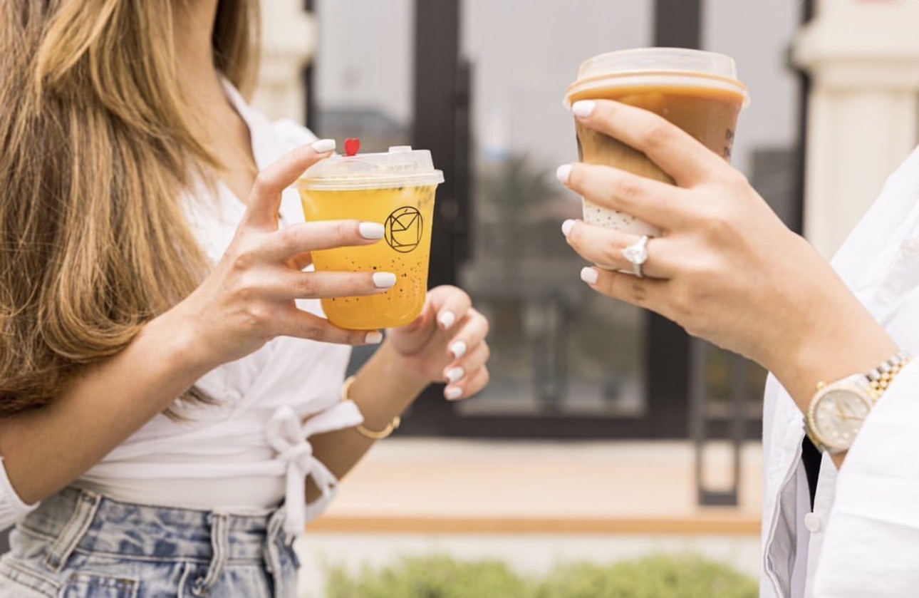 Two guests with Mélo branded drinks outside the salon